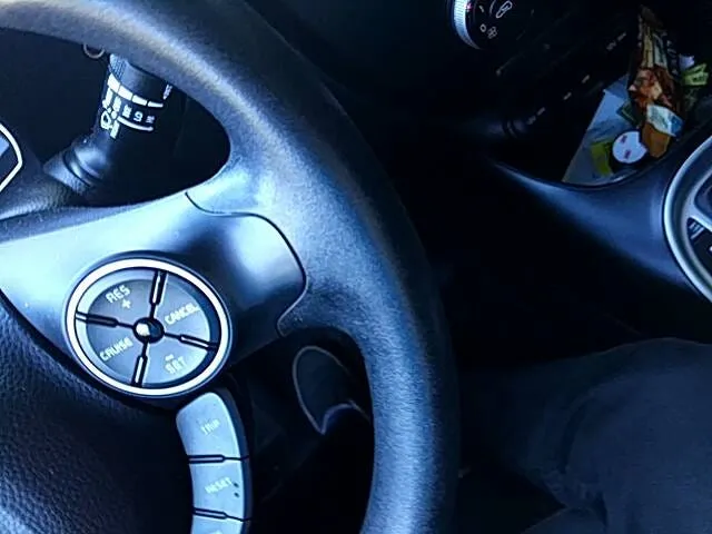 Close-up of a steering wheel and its cruise-control buttons, seen from the driver’s seat