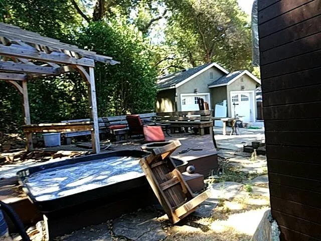 Backyard with a wooden deck, a pergola, a hot tub and a small shed