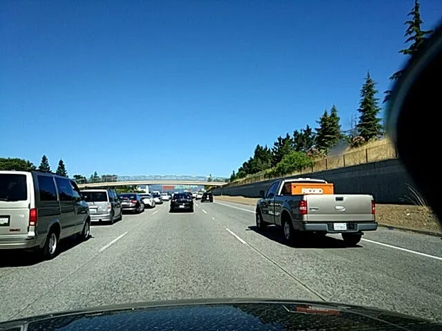 Dashcam view of busy freeway traffic on a sunny day, with a pickup truck ahead