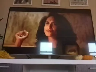 A TV showing a close-up of a woman talking and gesturing in a dimly lit scene