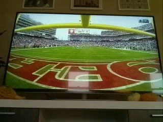 A TV showing a wide shot of the stadium from behind the goalposts, with a large team logo painted in the end zone
