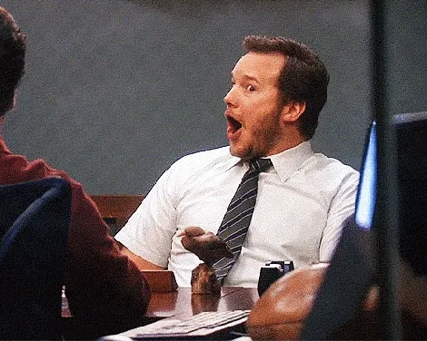 Animated GIF of a man at a conference table reacting with wide-eyed, open-mouthed amazement